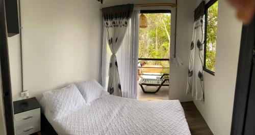 a bedroom with a white bed and a window at Cabaña el mirador del aguila in Quebradanegra