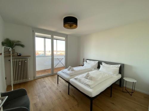 Dos camas en una habitación con una gran ventana. en LIBORIA I Über den Dächern Augsburgs, en Augsburg