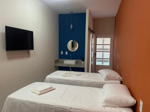 due letti in una stanza con una TV a parete di Pousada Sete Colinas a Bragança Paulista