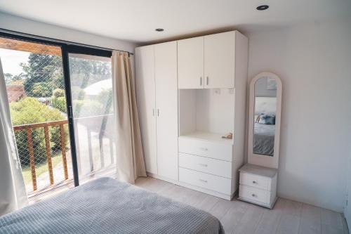 a bedroom with white cabinets and a large window at Check and home - Chapa II - 4 huéspedes con patio y parrilla in Chapadmalal