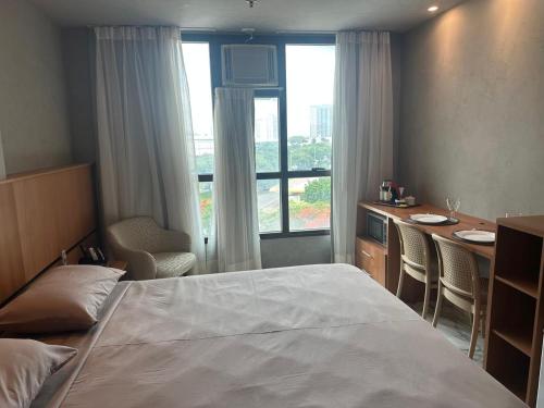 a bedroom with a bed and a desk and a window at Flat Comfort Taguatinga - Cama King - Sauna, academia e Piscina - Propriedade Particular 508 in Brasilia