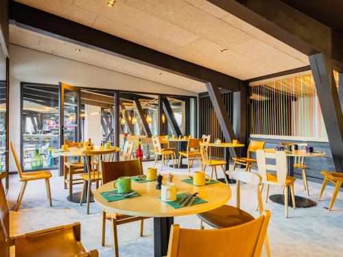 um restaurante com mesas, cadeiras e janelas em La Cachette, Friendly Hotel & Spa em Arc 1600