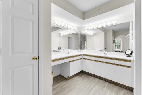 Baño blanco con 2 lavabos y espejo grande en Peaceful 2BR Condo by Golf Course Pools, en Branson
