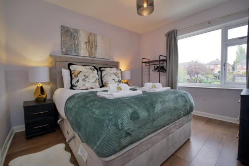 a bedroom with a large bed and a window at London Road Villa - Free Netflix, Private Parking, WiFi & Private Garden in Coventry