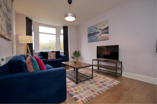 a living room with a blue couch and a tv at Whitley House - Stylish 3 Bedroom Home near Coventry City Centre in Coventry