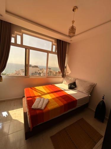 a bedroom with a bed with a colorful blanket and a window at Ami d'or Hostel in Taghazout