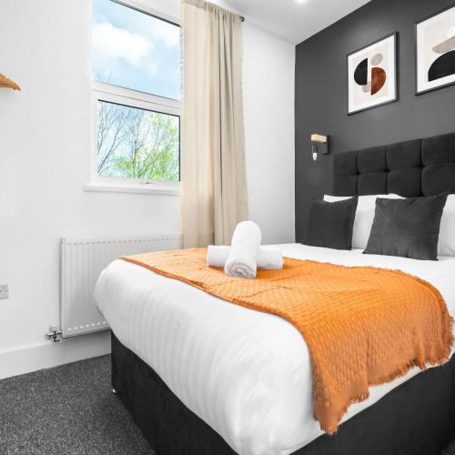 ein Schlafzimmer mit einem großen Bett mit einer orangefarbenen Decke in der Unterkunft 1 Bed Apartment - Street Parking - WiFi 49BG in Sleightholme