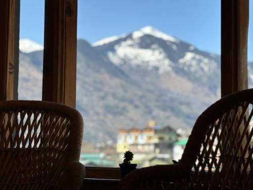 two chairs in front of a window with a mountain at Alpine suites in Nagar