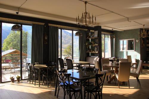 Un restaurante con mesas y sillas y grandes ventanales. en Hilltop Kazbegi, en Kazbegi
