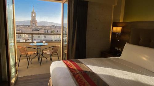 a hotel room with a bed and a balcony with a table at ARIQUEPAY HOTEL in Arequipa