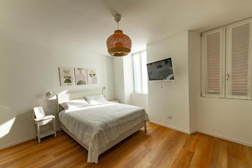 une chambre blanche avec un lit et une télévision dans l'établissement BGY Maison del Borgo 1, à Bergame