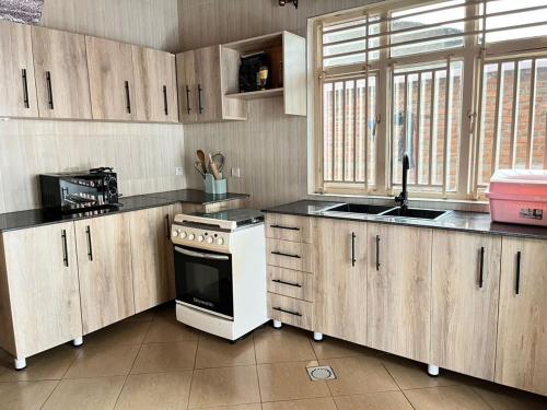 a kitchen with wooden cabinets and a white stove top oven at Kinigi Holiday Home in Kinigi