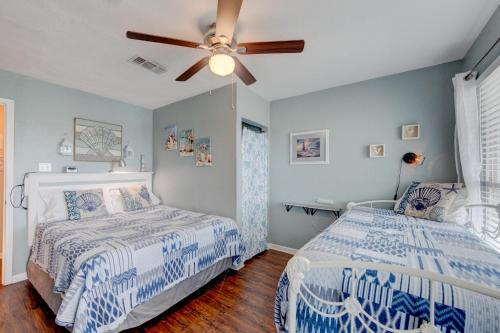 a bedroom with two beds and a ceiling fan at Beach Bum Headquarters in Mustang Beach