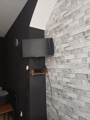 a tv on a brick wall in a room at Rajca Room's - Pokoje przy Jasnej Górze in Częstochowa