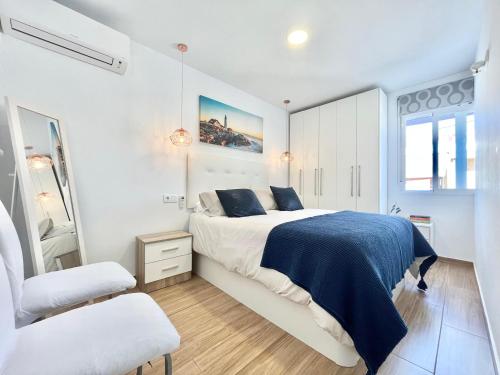 a white bedroom with a bed and a chair at Apartamento Caravaca in Santa Pola