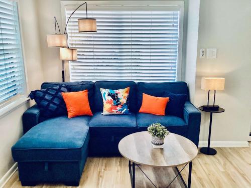 un sofá azul con almohadas naranjas en la sala de estar. en Marina Maison 2BDR Condo, en Clear Lake Shores
