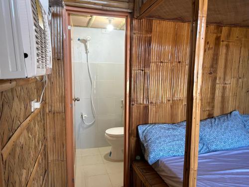 a small bathroom with a bed and a toilet at Beachfront Native house with pool in Nasugbu