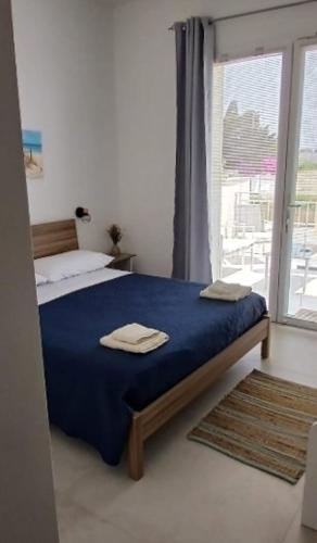 a bedroom with a bed with blue sheets and a window at L'Arco sul Mare in Porto Cesareo