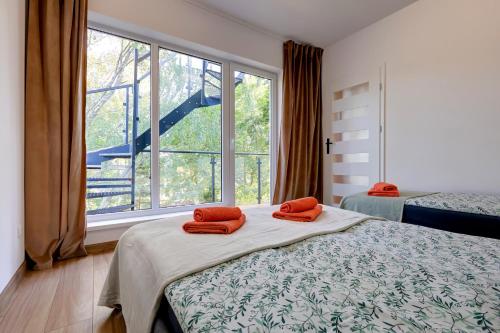 a bedroom with a bed with two orange towels on it at Poddąbek Comfort I Apartamenty z tarasem na dachu, ogródkiem, basenem zewnętrznym i wewnętrznym, salą zabaw i animacjami in Poddąbie