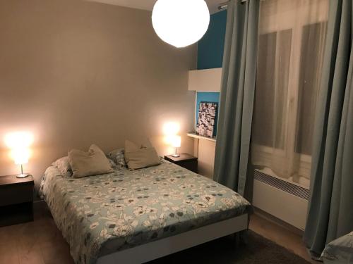 a bedroom with a bed with two lamps on it at Agréable appartement in Bobigny