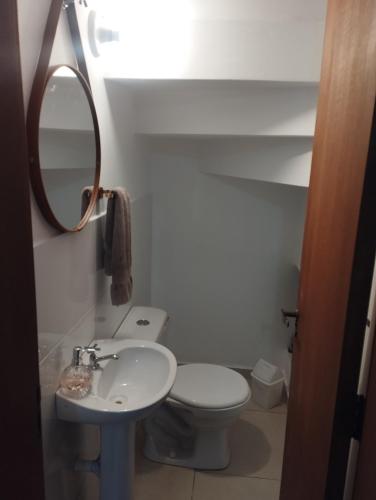 a bathroom with a toilet and a sink and a mirror at Sobrado Harmonia in Ponta Grossa