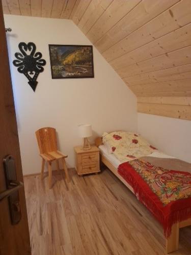 a bedroom with a bed and a chair in a attic at Domki nad Borem in Małe Ciche