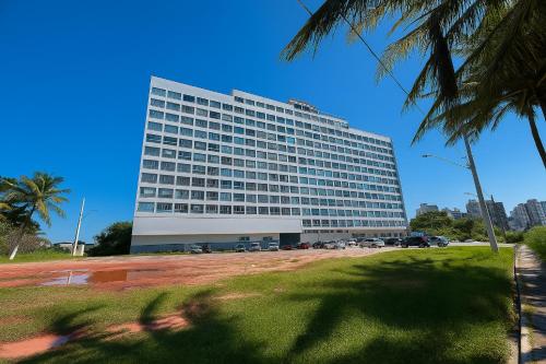 un grand bâtiment avec des voitures garées devant dans l'établissement Apartamento de Frente pro Mar com Vista Incrível - 10 min da Praia do Morro, à Guarapari