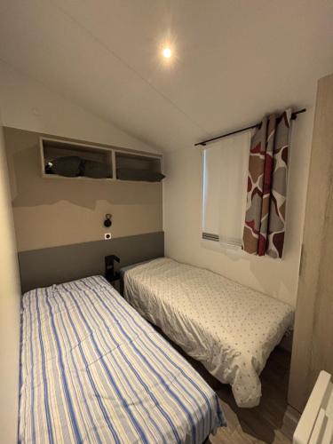 ein Schlafzimmer mit zwei Betten und einem Fenster in der Unterkunft mobil home in La Tremblade