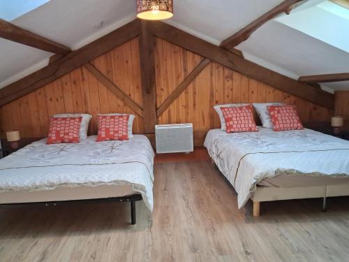 two beds in a room with wooden walls at Hebergement calme et verdoyant 
