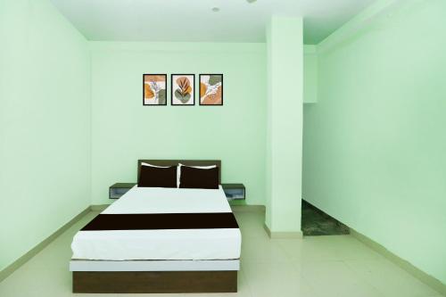 een bed in een witte kamer met twee foto's aan de muur bij Hotel O Royal Residency in Rānchī