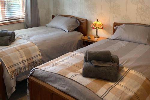 ein Schlafzimmer mit 2 Betten und einem Stuhl auf dem Bett in der Unterkunft Remarkable 2-Bed Cottage in tranquil setting in Wooler