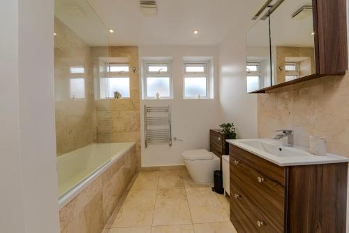 a bathroom with a tub and a toilet and a sink at Berwick Soho Suites by Aureva Residences in London