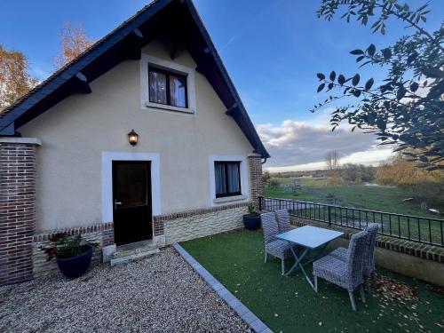 a small white house with a table and chairs at Duplex Tourny Gîte de charme pour 4 personnes au cœur de la campagne normande in Tourny