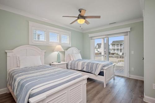 een slaapkamer met twee bedden en een plafondventilator bij Wait N Sea by Oak Island Accommodations in Oak Island