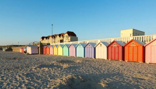 Una hilera de coloridas casetas de playa en la playa. en Marluis Mer - Apartment near dunes and beach, en Cucq