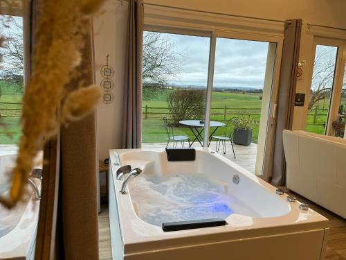 a bath tub with a view of a patio at Gîtes & SPA du bien-être in Courgains