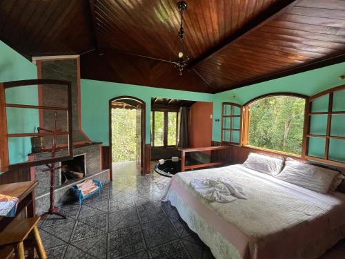 een slaapkamer met een bed in een kamer met ramen bij Pousada Brilho da Natureza in Visconde De Maua
