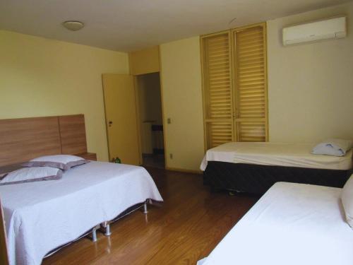 a bedroom with two beds and wooden floors at Solar dos Costais in Uberaba