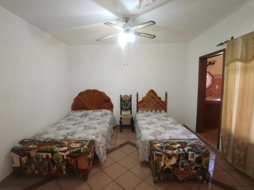 a bedroom with two beds and a ceiling fan at Casa Vergel in Temixco
