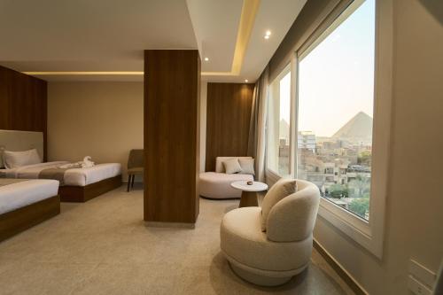 カイロにあるKemet Pyramids View Hotelの椅子と大きな窓が備わるホテルルームです。