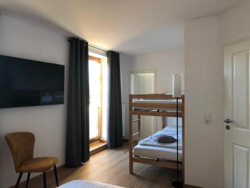 a small room with a bunk bed and a chair at Pension Zollhaus in Oy-Mittelberg