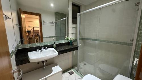 een witte badkamer met een wastafel en een douche bij Flat Vila da Serra in Nova Lima