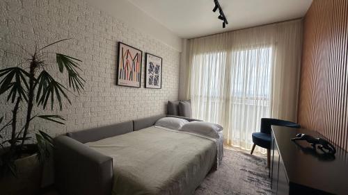 een slaapkamer met een bed en een groot raam bij Flat Vila da Serra in Nova Lima