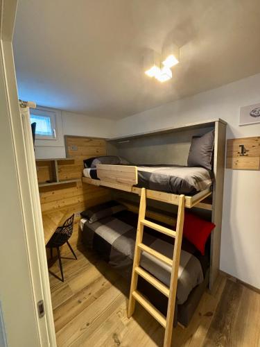 a room with two bunk beds and a stool at Fiore delle Alpi in Bellamonte