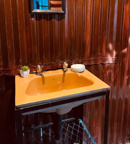 a yellow sink in a bathroom with wooden walls at Ewakanda Backpackers in Vereeniging