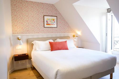 a bedroom with a white bed with a red pillow at Joli Môme in Paris