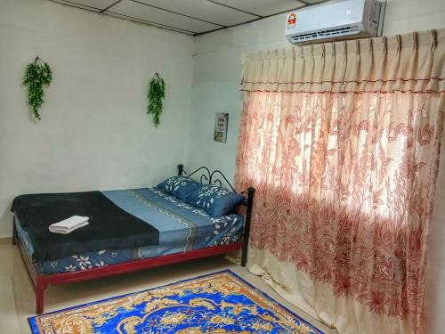 een slaapkamer met een bed met een gordijn en een tapijt bij Asyun Homestay 1 Double Storey House Sg Buloh Town in Sungai Buluh