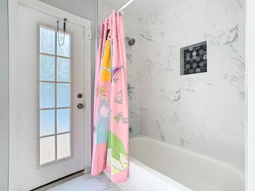 een badkamer met een roze douchegordijn naast een bad bij Casita mi Encanto a Cozy & Spacious House, 4-bedroom 3-Bath & pool in Kissimmee