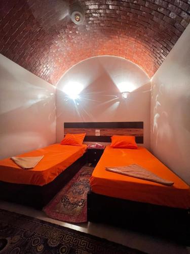 two beds in a room with a brick wall at Masa Nubian House in Aswan