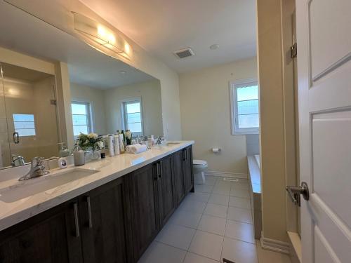 a bathroom with two sinks and a large mirror at Luxury 4BR Family Retreat in Thorold, Just 10 Mins from Niagara Falls, Clifton Hill & Wineries Free Wi-Fi, Free Parking in Thorold